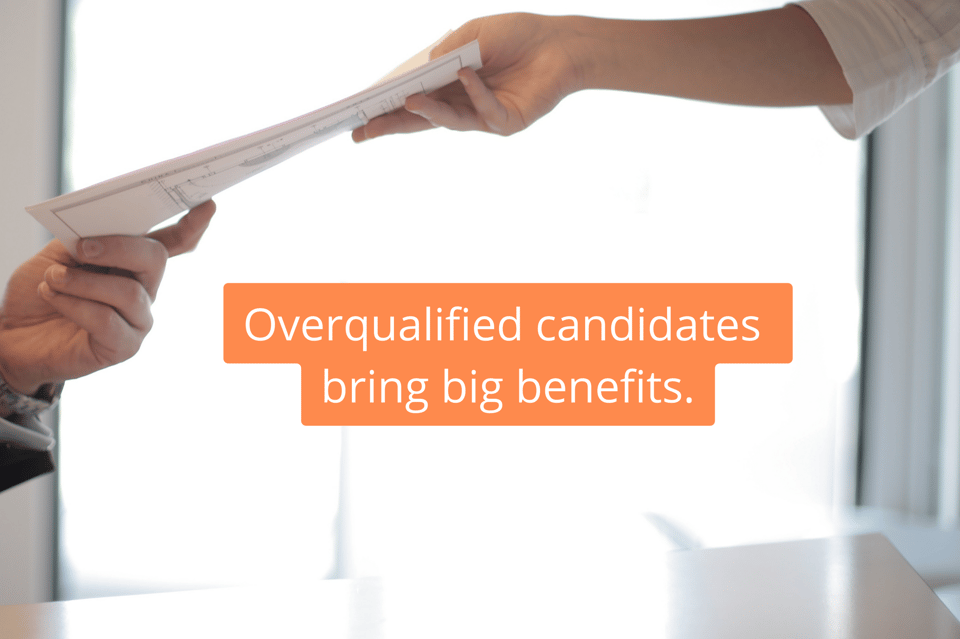 Text: Overqualified candidates bring big benefits. Picture of one person handing papers to another in office. 